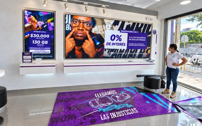 Local comercial con piezas gráficas de gran formato instaladas en la pared y en el piso, junto a una integrante del equipo