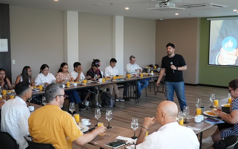 Charla en un evento empresarial con un orador y asistentes en mesas