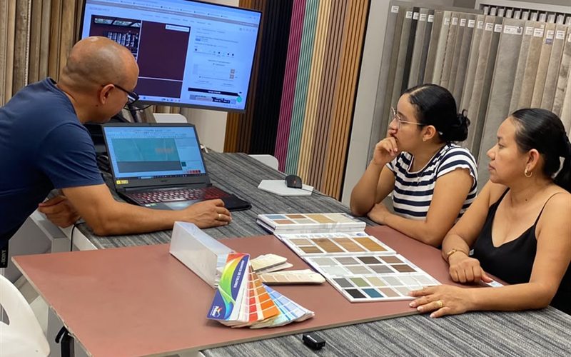 Reunión de asesoría con muestras de color y pantalla junto a dos clientas